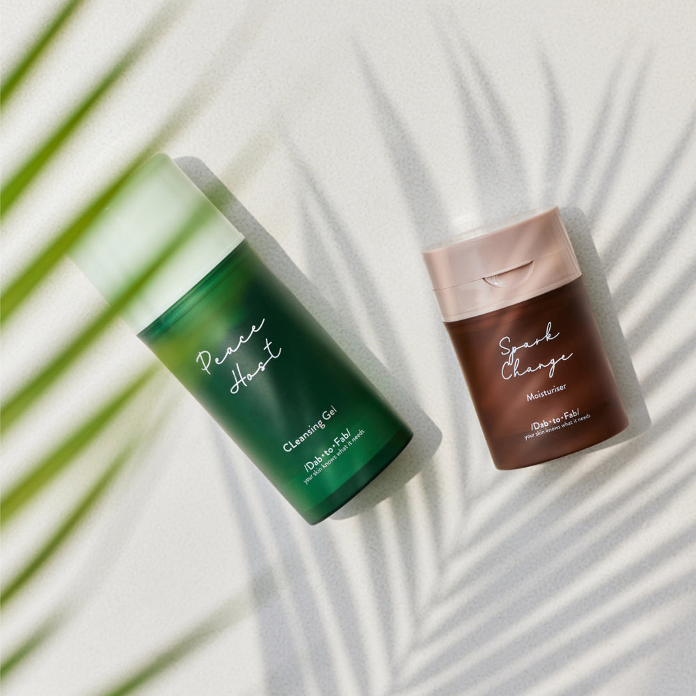 Dab to Fab Fabulous Skin Set featuring Peace Host Cleansing Gel in green and Spark Change Moisturizer in brown, placed next to each other on a white background with plant shadows.